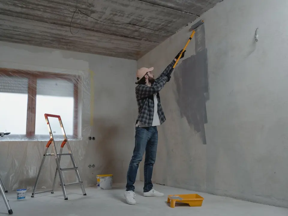 Contractor painting an interior wall with a roller during a home renovation