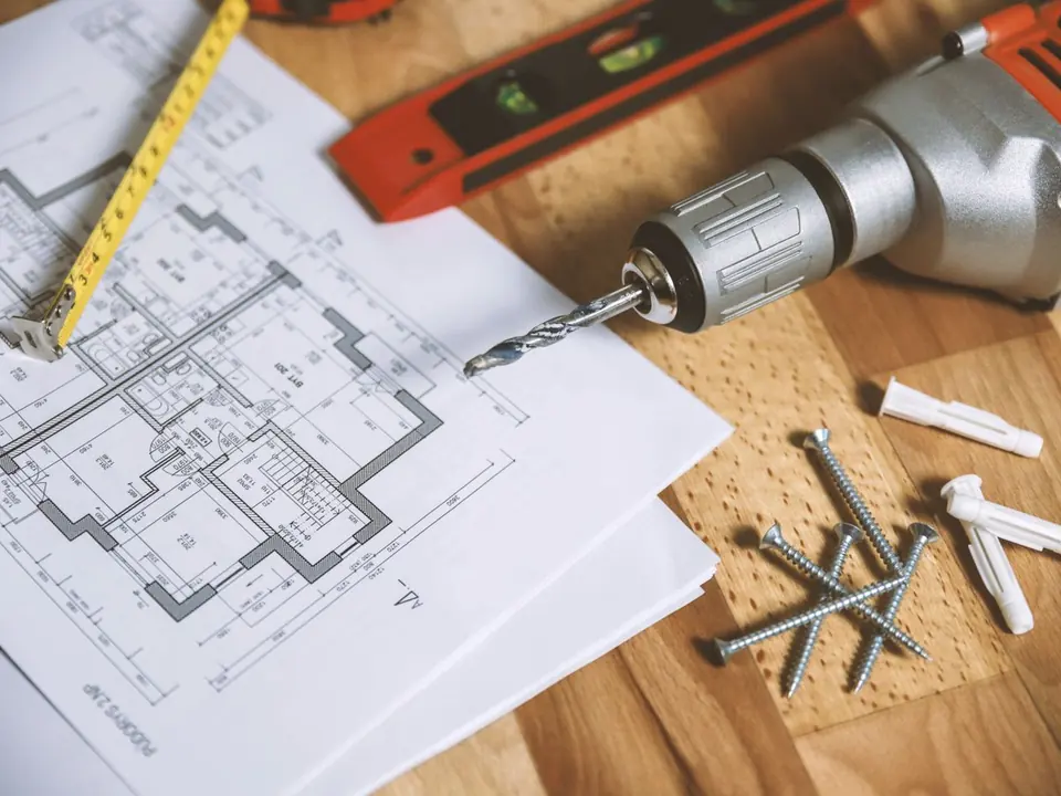 Home renovation floor plans with a drill, tape measure, and hardware on a workbench